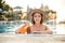 Young woman applying sunscreen lotion sitting on poolside. Sunscreen solar cream uv protection concept