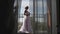 A young woman approaches the window, opens to a balcony, enjoying. Morning bride waiting for wedding