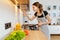 Young woman in apron cooking healthy food at modern home kitchen. Preparing meal with frying pan on gas stove. Concept of domestic