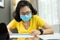 Young Woman Architect designer wear eyeglasses, yellow shirt, blue surgical mask working on blueprints for interior design project