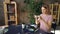 Young woman is arranging pictures, take-out coffee, sun glasses, professional camera and marker on table and shooting