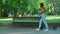 A young woman arriving in park on electric push scooter, sits on a park bench and reading book