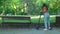 A young woman arriving in park on electric push scooter, sits on a park bench and reading book