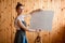 Young woman artist stands near easel and holds the canvas