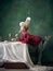 Young woman as Marie Antoinette on dark background. Retro style, comparison of eras concept.