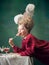 Young woman as Marie Antoinette on dark background. Retro style, comparison of eras concept.