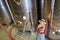 Young woman as a winemaker trainee in front of a fermentation tank