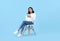 Young woman Asian happy and interested in thinking.While her holding notebook sitting on white chair isolate on bright blue