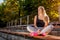 Young woman athlete having rest after running on sportsground in summer. Happy girl sitting on bench and relaxing