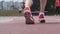 Young woman athlete legs in red snikers that starts running at athletics track in a day training in slow motion close up