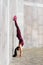 Young woman athlete performs handstand exercise on the street near the wall