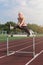 Young woman athlete runnner running hurdles