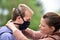 A young woman attaching a protective DIY facemask onto her husband's face for protection against coronavirus.