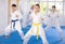 Young woman attendee of karate classes practicing kata standing in row with others