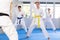 Young woman attendee of karate classes practicing kata standing in row with others