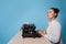 young woman author at a typewriter, writes a text. A writer at a table with a vintage typewriter