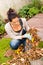 Young woman autumn gardening cleaning leaves