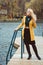 Young woman in autumn on pier looks away