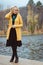 A young woman in autumn on pier looks down and adjusts her hair