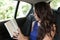 Young woman in back seat of car reading paperback