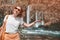 young woman with backpack admires a beautiful and powerful waterfall in the jungle. The upper Duden Waterfall in Antalya