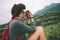 Young woman with backpack and headphones taking photo of volcano in the wild