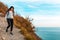 A young woman with a backpack on her back descends a rocky slope. In the background, the sea and the sky. Copy space. Concept of