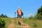 A young woman with backpack and hiking poles walking