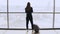 Young woman with backpack near terminal window. Caucasian female tourist using smartphone in airport lounge. Travel. 4K.