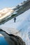 A young woman with backpack and pole hiking on iceberg and snow and enjoying the views of the Andes mountains and lake