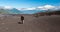 A young woman with backpack and pole hiking on iceberg and snow and enjoying the views of the Antuco volcano black volcano desert.