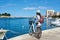 Young woman with backpack riding city bicycle near sea