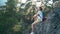 Young woman with a backpack sitting on a rocky mountain and enjoying fresh air