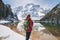 Young woman with backpack on the snowy shore of Braies lake