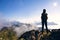 Young woman with backpack standing on cliff\'s edge