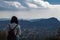 Young woman with backpack watching the city from mountain