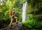 Young woman backpacker looking at the waterfall in jungles.