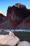 Young woman backpacker resting by Hance Rapids in the Grand Canyon.