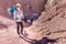 Young woman backpacker tourist standing stone desert canyon trail.