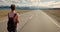 Young woman backpacker walking on road.