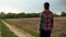 A young woman with a bag is walking along a country road. The girl returns home along a rural road with a bag in her hands.