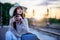 Young woman with baggage on train station using smart phone