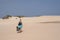 Young woman with bags is hiking in sand-dunes of desert, Fuerteventura, Spain