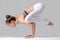 Young woman in Bakasana pose, grey studio background