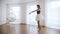 Young woman ballerina training in bright studio. Performing the pirouette