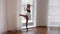 Young woman ballerina warming up in the studio standing by the window