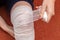 A young woman bandages a bandage on her injured knee. Top view. Self-help in case of a knee injury