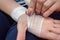 A young woman bandages her injured hand with a white gauze bandage. Close-up