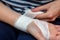 Young woman bandaging her wrist. Wound care bandage, control bleeding. Bandaging a wrist wound with a gauze bandage. Close-up,