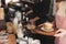 Young woman barista wearing apron standing at coffee shop holding cup serving